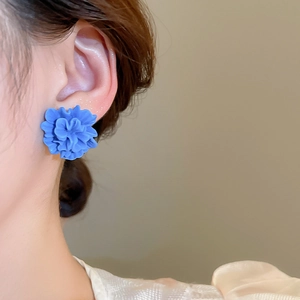 Detailed view of 3D blue resin flower stud earring worn on ear with matte petals