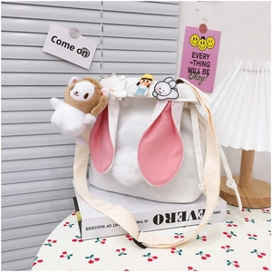 Detail of white canvas bucket bag with rabbit ears, plush charm and cute badges