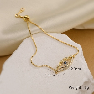 Detail shot of gold evil eye bracelet with blue zircons on a white stone background