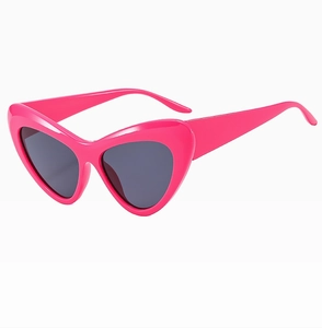 Detail of pink heart-shaped sunglasses with dark grey lenses and smooth plastic finish