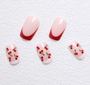 Short square press-on nails featuring red French tips and cute cherry pattern designs