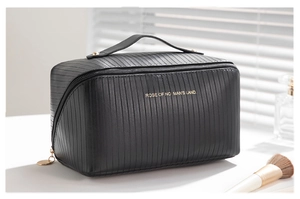Close-up of black textured toiletry bag with vertical stripes and golden lettering