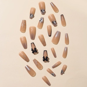 Nude coffee gradient press-on nails with 3D black bows and glitter accents