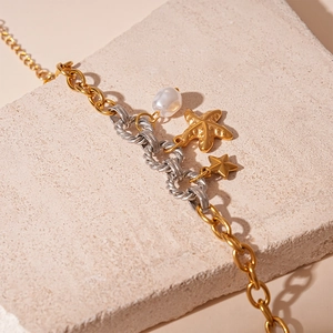 Detail of beach-style steel bracelet with irregular pearl, starfish and star charms