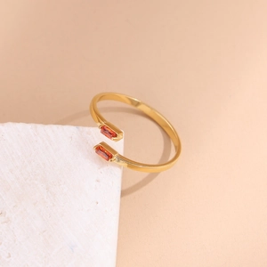 Detail of gold-plated open ring featuring two rectangular red zircon stones on a white stone