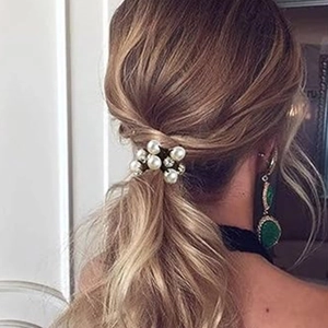 Detailansicht eines eleganten Haargummis mit Perlen und Steinen am Pferdeschwanz
