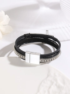 Detail of multi-layer black leather bracelet with silver cross and magnetic clasp