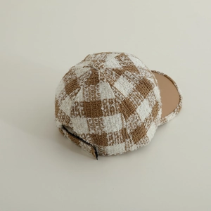 Close-up of tweed plaid pattern with brown leather brim and adjustable back buckle