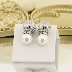 Macro shot of vintage pearl stud earrings with textured steel finish and rhinestones