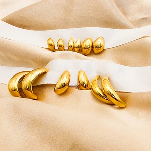 Detail shot of various 18K gold waterdrop and crescent hoop earrings on silk ribbon