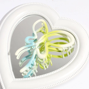Detail of blue-yellow gradient butterfly hair claw clip on a heart-shaped mirror base