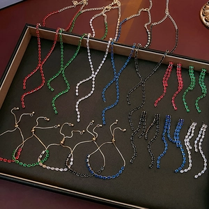 Flat lay of shimmering tassel jewelry sets in five colors on a black tray