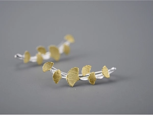 Detailed macro view of gold ginkgo leaf ear climbers with brushed metallic texture