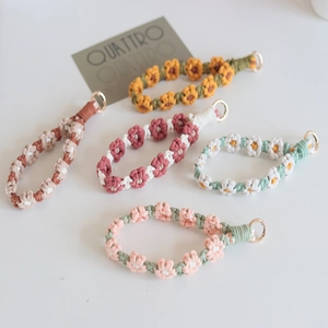 Detailed shot of handmade woven daisy charms in multiple colors with gold spring buckles
