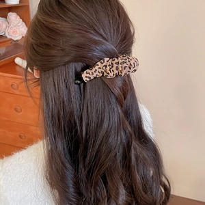 Detailed back view of a leopard print fabric hair clip on brown curly hair for styling