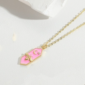 Detail of pink hexagon pendant with gold bee and moon charms on a delicate chain