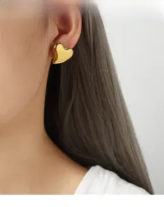 Polished 18K gold heart-shaped stud earrings worn by a model for a chic minimal look