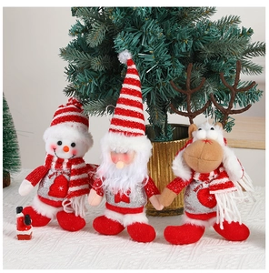 Three plush Christmas ornaments of Santa, snowman, and reindeer on a festive table