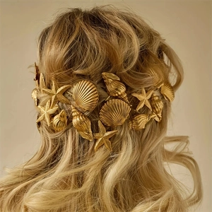 Detailed view of a golden shell and starfish hair accessory on blonde wavy hair