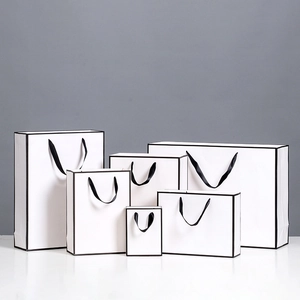 Minimalist white paper gift bags with black borders and handles in six different sizes