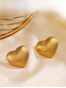 Macro detail of gold heart earrings with vertical striped texture on beige silk fabric