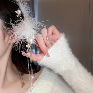 Detailed view of feather and pearl ear cuff featuring elegant long metal tassel chains