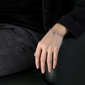 Minimalist silver paperclip chain bracelet with round coin pendant worn on wrist
