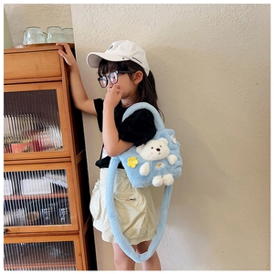 Detail of light blue plush children's crossbody bag with a cute 3D bear on female model