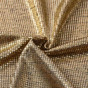 Makroaufnahme von goldfarbenem Metallgewebe mit feiner Paillettenstruktur und Glanzeffekt