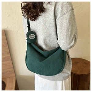 Détail de la texture en velours côtelé vert foncé et du petit sac rond sur la bandoulière