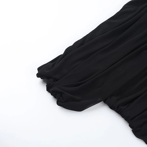 Detailed macro view showing the pleated mesh fabric texture of the black off-shoulder top