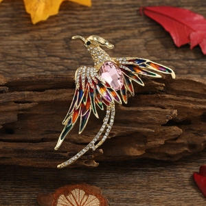 Detailed close-up of a phoenix brooch featuring colorful enamel feathers and pink gemstones