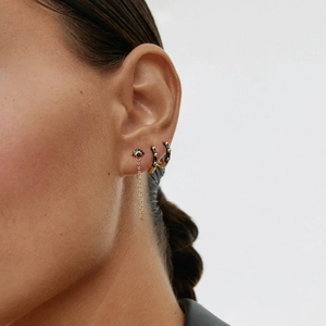 Detailed macro view of trendy gold ear cuffs with black stones and long tassel chain