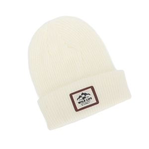 Detailed view of cream knit beanie featuring a mountain bear leather adventure patch