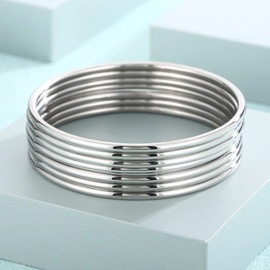 Close-up of 7-piece set minimalist silver stainless steel bracelets on display base
