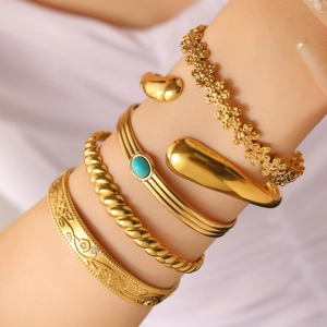 Macro shot of gold stacked bracelets featuring turquoise stone and floral patterns