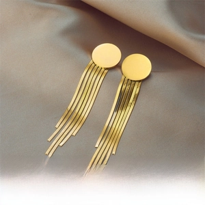 Detail of gold fringe earrings with round studs and hanging snake chains on silk fabric