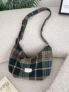 Retro plaid hobo crossbody bag with adjustable strap on a cream textured sofa