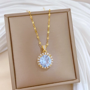 Close-up of golden titanium necklace with a large round zircon pendant on a beige jewelry box