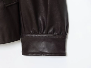 Detailed macro view of deep brown leather jacket cuff showing stitching and texture