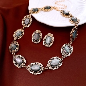 Detailed view of vintage gold necklace and earring set with gray resin oval gemstones
