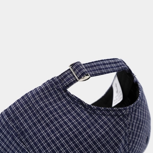 Detailed close-up of dark blue plaid baseball cap with adjustable silver metal buckle