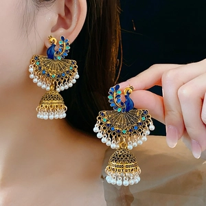 Macro detail of gold vintage peacock earring with colorful enamel and pearl accents