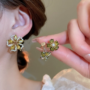Detail of silver stud earrings with emerald green floral stones and crystal accents