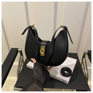 Detail of a black crescent leather handbag with gold metal clasp on a chair