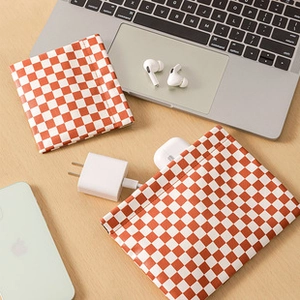 Close-up of checkerboard makeup bags organizing chargers and wireless earphones on desk