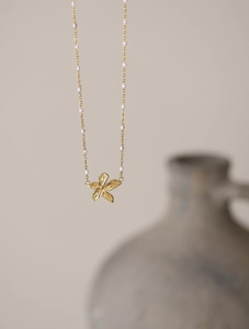Detail of 18K gold flower pendant necklace with elegant white round beads on fine chain