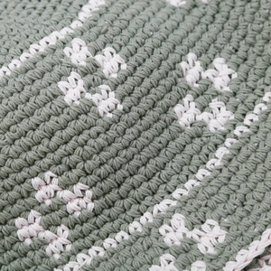 Close-up of handmade crochet fisherman hat showing detailed floral knit and green yarn