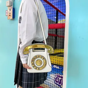 Close-up of a white vintage telephone crossbody bag with gold dial and receiver details