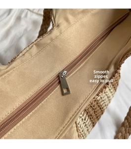 Detail of high-quality smooth metal zipper closure on vertical striped straw beach tote